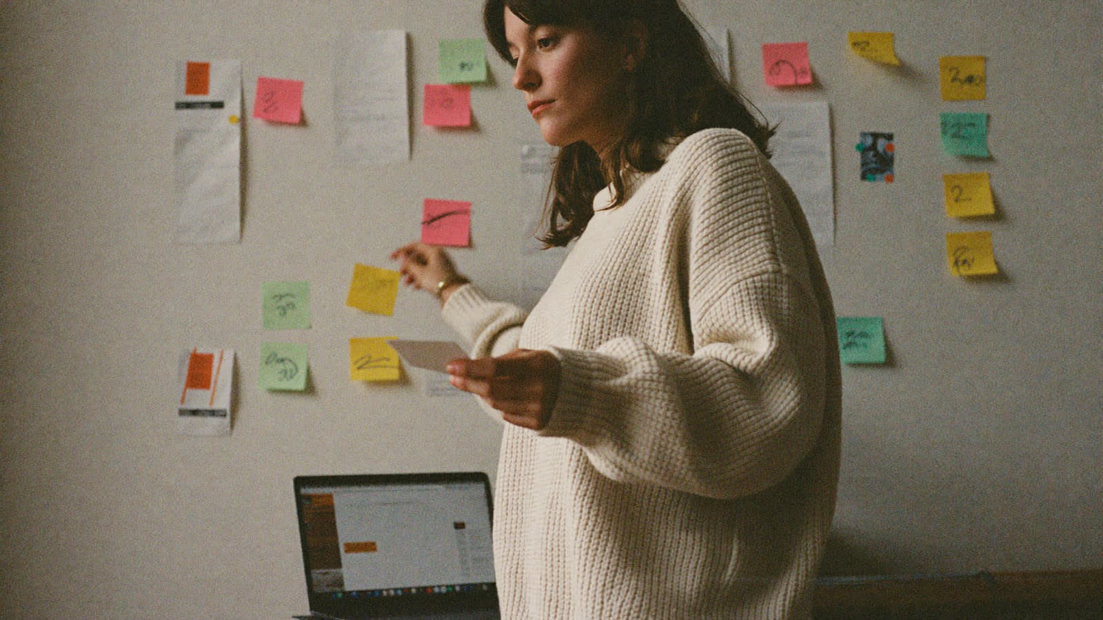 Fundadora eligiendo entre notas organizadas en columnas sobre una pared